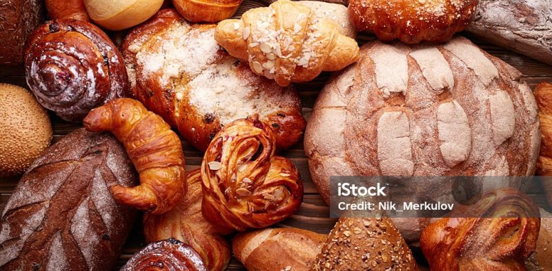 Fresh tasty bread and buns over wooden background